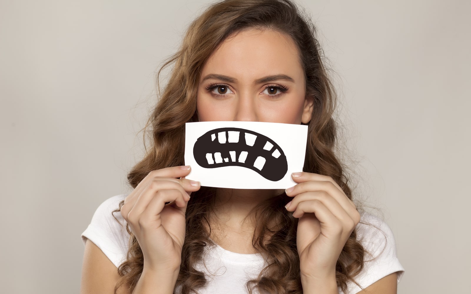 Woman holding frowning image of bad teeth